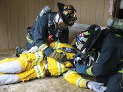 Figure 1. Realistic scenario-based training is a must for rapid intervention, but this also necessitates a closer eye be kept on the safety of the participants. Here, firefighters practice assessment and changing over of an air supply, skills that often are neglected during training, but require emphasis.