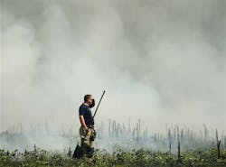 An Athens firefighter wipes his brow as he takes a break from battling a field fire near Tanner High School in Limestone County.