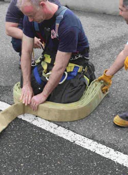 Photo 1. When packing the first hose pack, start with the female coupling at your left ankle and continue to go from one ankle to the other. Photo 1. When packing the first hose pack, start with the female coupling at your left ankle and continue to go from one ankle to the other.