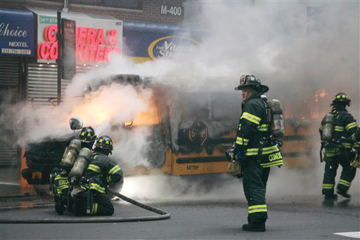 Firefighters hose down a burning school bus in midtown Manhattan in New York , Tuesday, Nov. 22, 2011. Police blocked off the busy area around 7th Avenue and 35th Street for about a half-hour before reopening it. The Fire Department said there were no injuries.