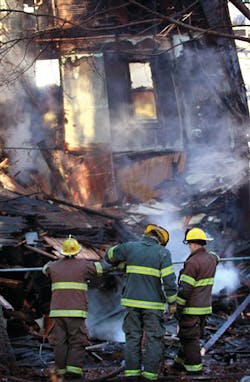 Worcester firefighters stand near the fire damaged remains of a multi-family home. Worcester firefighters stand near the fire damaged remains of a multi-family home.