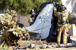 Firefighters remove a tarp from the remains of a small aircraft that crashed in the front yard of a northeast Phoenix home.