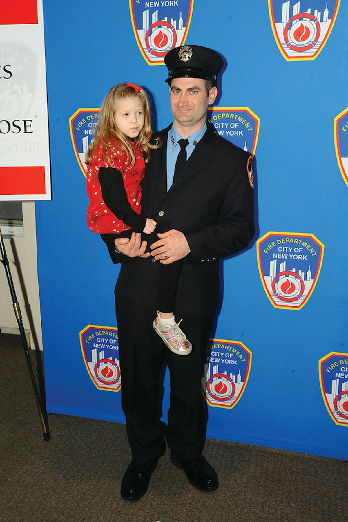FDNY Firefighter James Wildes holds 6-year-old Alise Mareerose Williams of Evansdale, IA, during the Honor Roll of Life ceremony. Firefighter Wildes donated life-saving stem cells to Alise in 2009.