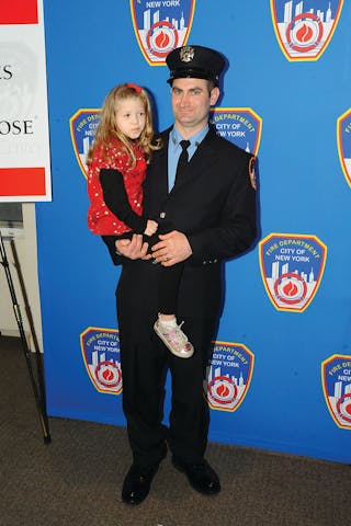 FDNY Firefighter James Wildes holds 6-year-old Alise Mareerose Williams of Evansdale, IA, during the Honor Roll of Life ceremony. Firefighter Wildes donated life-saving stem cells to Alise in 2009.