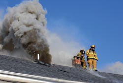 After cutting a ventilation hole, two firefighters prepare to exit the roof. After cutting a ventilation hole, two firefighters prepare to exit the roof.