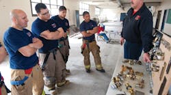 A fire instructor (right) discusses forcible entry skills at Firehouse World in San Diego. A company officer in his community, he travels to teach others around the country.