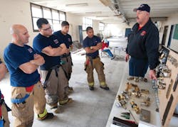 A fire instructor (right) discusses forcible entry skills at Firehouse World in San Diego. A company officer in his community, he travels to teach others around the country.