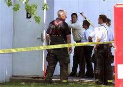 Firefighters gather by the door of Arens Control in Arlington Heights, Ill. where a fatal explosion occurred on May 22.