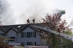 Firefighters battled a two-alarm fire at a condominium complex on May 16 where two firefighters were injured and another came out unscathed after falling through the roof.