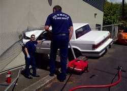 Firefighters discuss how to remove a man from a car after he crashed it into TVW Studios in Olympia, Wash. on May 9.