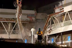 A rescue worker watches as a demolition crane as it tears into part of the Algo Centre Mall, in Elliot Lake, Ontario on June 26.