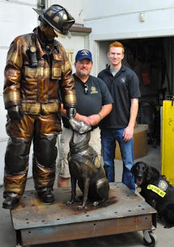 Arson Investigator Jerry Means, left, and Firefighter Austin Weishel stand next to the monument they both helped create.