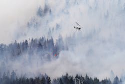 A firefighting helicopter, operated by the Washington State Department of Natural Resources, works to supress the Taylor Bridge Fire east of Cle Elum, Wash. on Aug. 13.