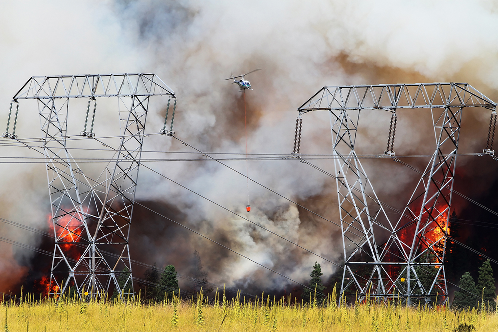 A firefighting helicopter, operated by the Washington State Department of Natural Resources, works to supress flames from the Taylor Bridge Fire east of Cle Elum, Wash. on Aug. 13.