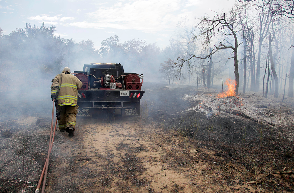 A firefighter works to battle a wildfire just west of Mannford, Okla. on Aug. 5.