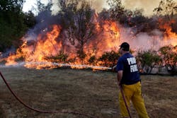 A Prue firefighter battles a blaze as it nears homes in the area of Highway 48 and W 31st Street in Mannford, Okla. on Aug. 5.