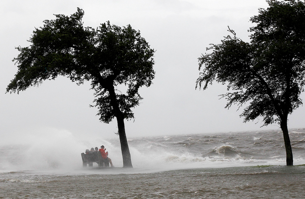 People sit on a bench along the seawall in the storm surge from Isaac, on Lakeshore Drive along Lake Pontchartrain in New Orleans on Aug. 28.