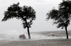 People sit on a bench along the seawall in the storm surge from Isaac, on Lakeshore Drive along Lake Pontchartrain in New Orleans on Aug. 28.