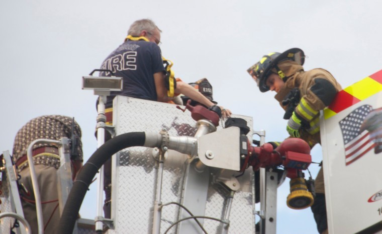 A firefighter from the Pascua Pueblo Fire Department, right, helps a victim from the bucket of a Green Valley ladder truck.