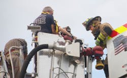 A firefighter from the Pascua Pueblo Fire Department, right, helps a victim from the bucket of a Green Valley ladder truck.