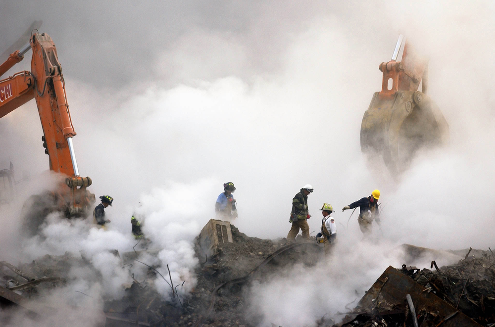 Firefighters make their way over the ruins and through clouds of smoke at the World Trade Center on Oct. 11, 2001.