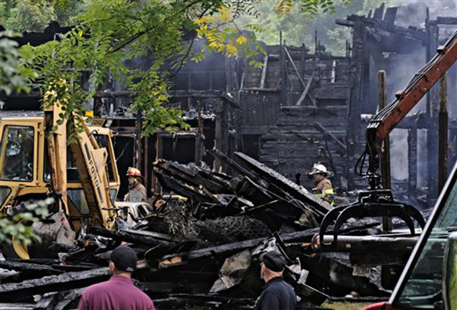 Firefighters search the scene of the fire in Uxbridge, Mass., for a missing woman and child on Sept. 4.