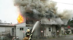 A West Virginia fire chief operates a hoseline at a daytime building fire where staffing issues require senior and rookie firefighters to work together.