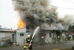 A West Virginia fire chief operates a hoseline at a daytime building fire where staffing issues require senior and rookie firefighters to work together.