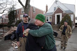 New York firefighter John Dwyer, facing camera, hugs New Orleans firefighter Robert Tourres, after a group of New Orleans firefighters assisted in the cleanup of the Dwyer family home, flooded in Superstorm Sandy, in the Belle Harbor section of Queens, N.Y., Wednesday, Nov. 28, 2012. New Orleans firefighters Bill Spiers, left, and Bruce Hurley, Sr. joined in the cleanup.