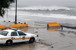 A police officer watches from his patrol car as the rough Atlantic Ocean threatens streets on Oct. 29 in Cape May, N.J.
