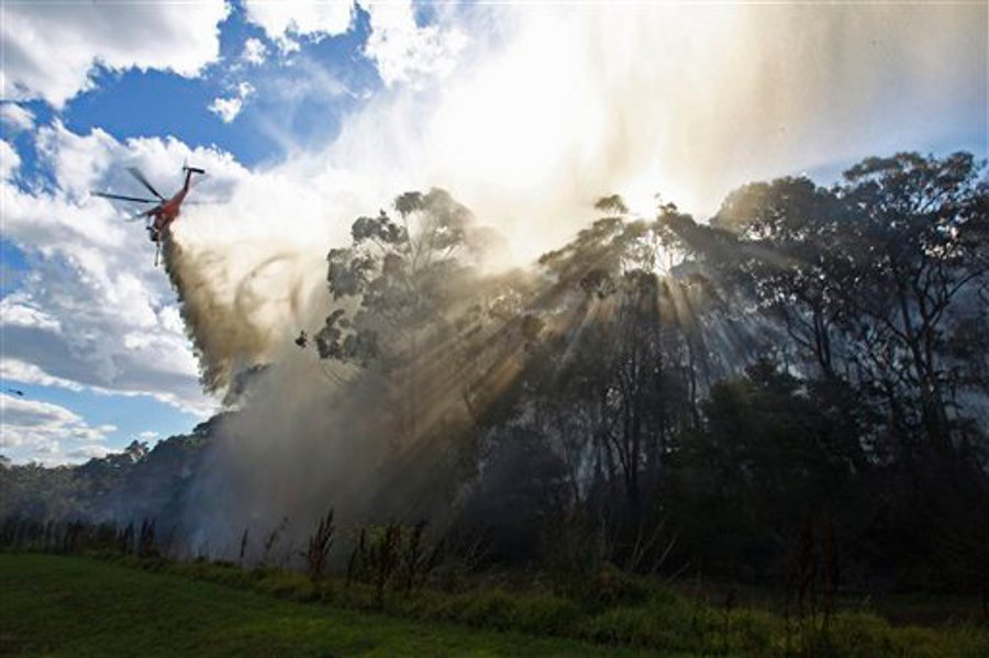 A helicopter drops water onto a smoldering fire in the Lane Cove National Park in Sydney, Australia on Dec. 5.