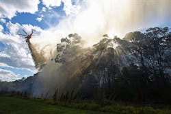 A helicopter drops water onto a smoldering fire in the Lane Cove National Park in Sydney, Australia on Dec. 5. A helicopter drops water onto a smoldering fire in the Lane Cove National Park in Sydney, Australia on Dec. 5.