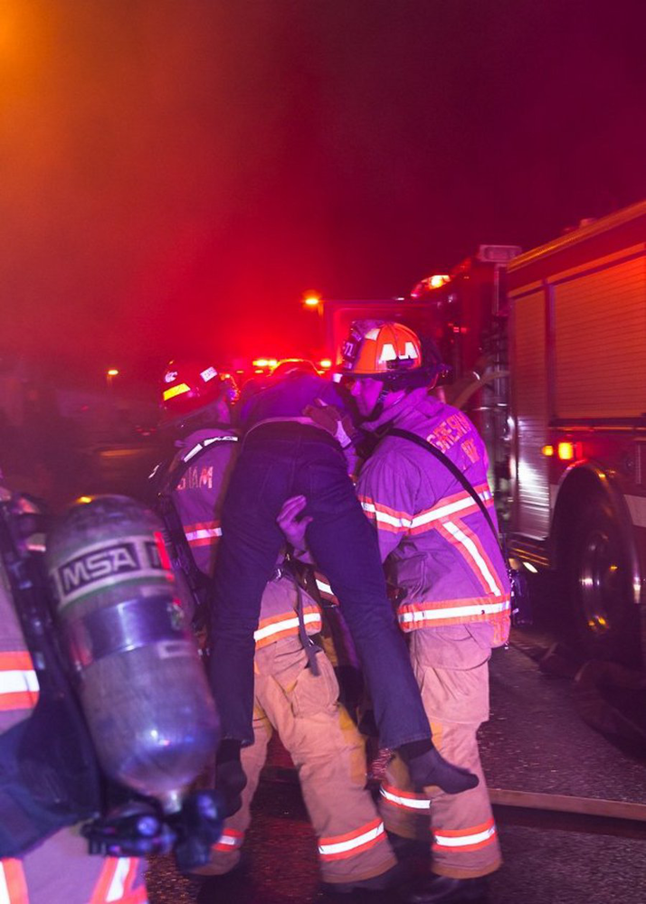 Firefighters rush Keith Moore away from a burning building after pulling him out on Nov. 29 in Gresham, Ore.