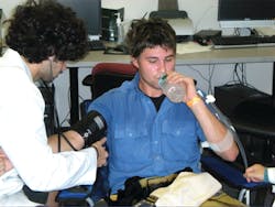 Figure 1. During treadmill walking, participants wore full personal protective equipment (PPE). During recovery periods, participants doffed their helmet, gloves, hood and bunker coat and sat in front of a fan and rehydrated. This participant was wearing a cotton T-shirt and a station uniform under the PPE. Figure 1. During treadmill walking, participants wore full personal protective equipment (PPE). During recovery periods, participants doffed their helmet, gloves, hood and bunker coat and sat in front of a fan and rehydrated. This participant was wearing a cotton T-shirt and a station uniform under the PPE.
