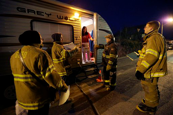 Gerritsen Beach Volunteer Fire Department representatives check on local resident Debbie Krieger, who has been living in a trailer while her Superstorm Sandy-damaged house is being rebuilt, on an bitter cold night when temperatures were expected to dip into the single digits in New York, Thursday, Jan. 24, 2013. Visiting firefighter Mike Smith, of the Richmond, Mass., Fire Department, second from right joined the group. The firefighters had donated blankets and space heaters available for those who needed them.