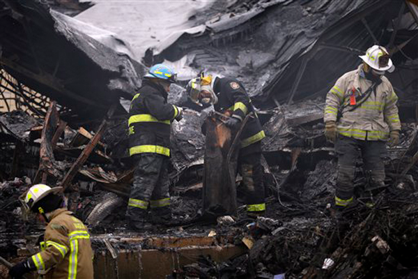 Investigators look over the aftermath of a fire at the Melrose Shopping Center Friday, Jan. 25, 2013, in Cheltenham, Pa. The fire at a shopping center in suburban Philadelphia has damaged nearly a half dozen stores and left one person dead. Officials say police pulled one person from the blaze and that the victim later died at a hospital. Two firefighters also suffered minor injuries. (AP Photo/Matt Rourke)