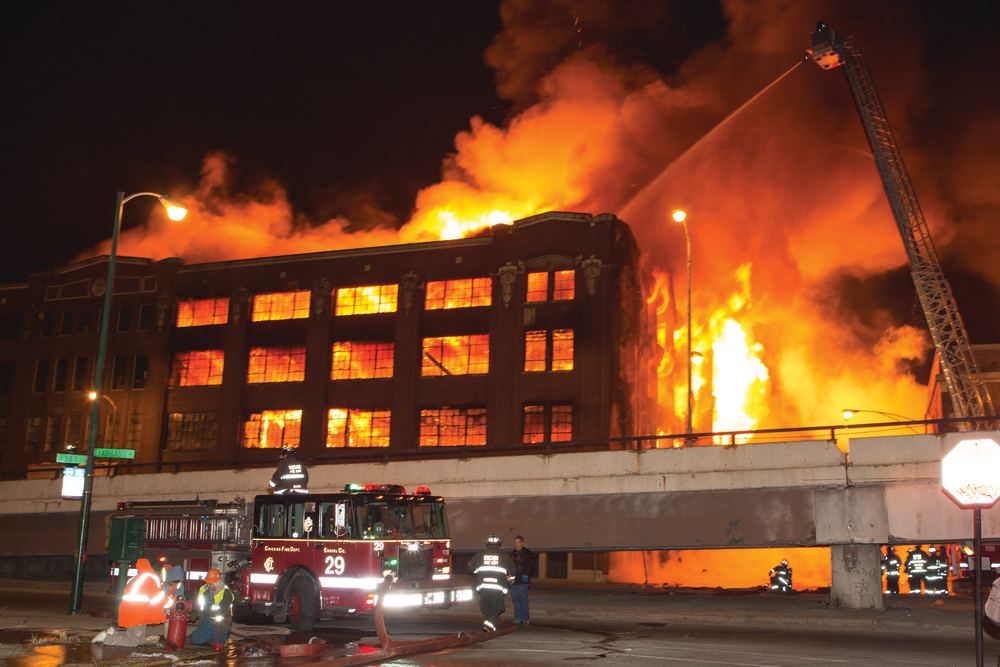 Apparatus is positioned away from the building as the fire spreads to the upper floors.