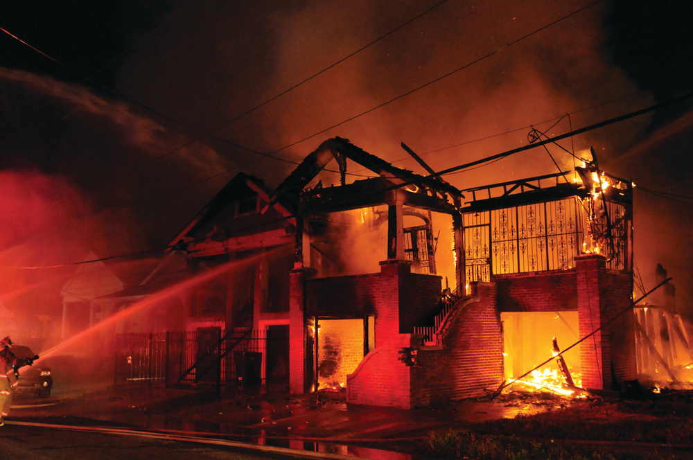 Firefighters in New Orleans, LA, battle a four-alarm fire that destroyed a pair of vacant two-story, wood-constructed dwellings. One of the homes totally collapsed.