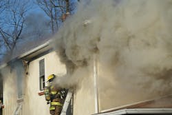 Photo 1. Turbulent smoke vents out the window where firefighters had been searching for fire extension.