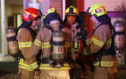 Eagan firefighters wearing the new European-style helmets, gather at the scene of a two-alarm apartment recently.