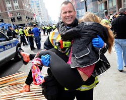 Boston Firefighter James Plourde carries an injured girl away from the scene after a bombing near the finish line.