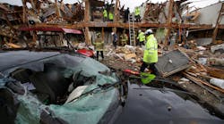 A smashed car sits in front of an apartment complex that was destroyed by the explosion in West, Texas, as firefighters conduct a search and rescue Thursday.