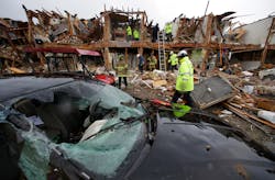 A smashed car sits in front of an apartment complex that was destroyed by the explosion in West, Texas, as firefighters conduct a search and rescue Thursday.