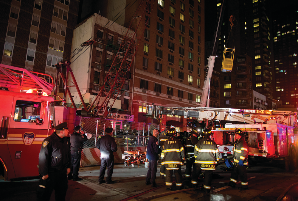 A construction transport bucket, right, is moved into place at the scene where a worker at a subway construction project was trapped underground. The worker was rescued after being trapped up to his chest in debris for several hours. One hundred fifty rescuers descended on the site to free the trapped worker.