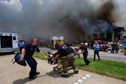 A firefighter is wheeled to an ambulance after fighting a fire at the Southwest Inn, Friday, May 31, 2013, in Houston.