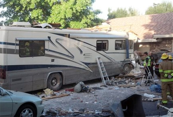 This image provided by the Utah Highway Patrol shows a crash site Friday May 24, 2013 in St. George, Utah. Two people died after the RV carrying 10 people went off the highway and crashed through a fence and into the garages of several townhomes. A Utah Highway Patrol spokesman said the crash occurred just before 6 a.m. Friday and the two people who died were adults riding in the front of the motorhome.