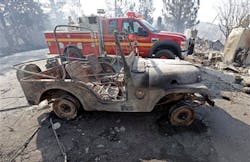 A burned-out Jeep is parked next to a Los Angeles County Fire Department rig at one of at least five structures destroyed or severely damaged in what has been called the Powerhouse fire.