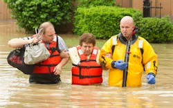 Fort Wayne firefighters Jerry Shultz, left, and Brian Sorgen, right, help Karen Hudda wade through the flood waters in front of her West State Blvd. home on Saturday, June 1, 2013 in Fort Wayne, Ind.