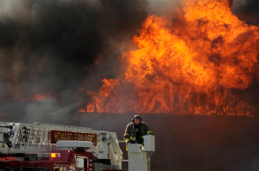 A firefighter from the Howard Fire Department operates a ladder truck as flames rip through the roof to the Northern Pines apartment complex in Howard, Wis.