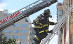 A firefighter climbs a ladder during a truck company operations class in a row of vacant homes in Baltimore Tuesday.